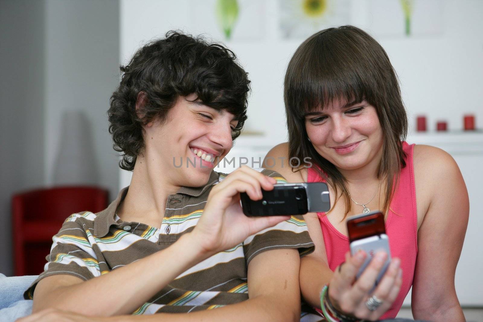 Teens looking at pictures on their mobile phones by phovoir