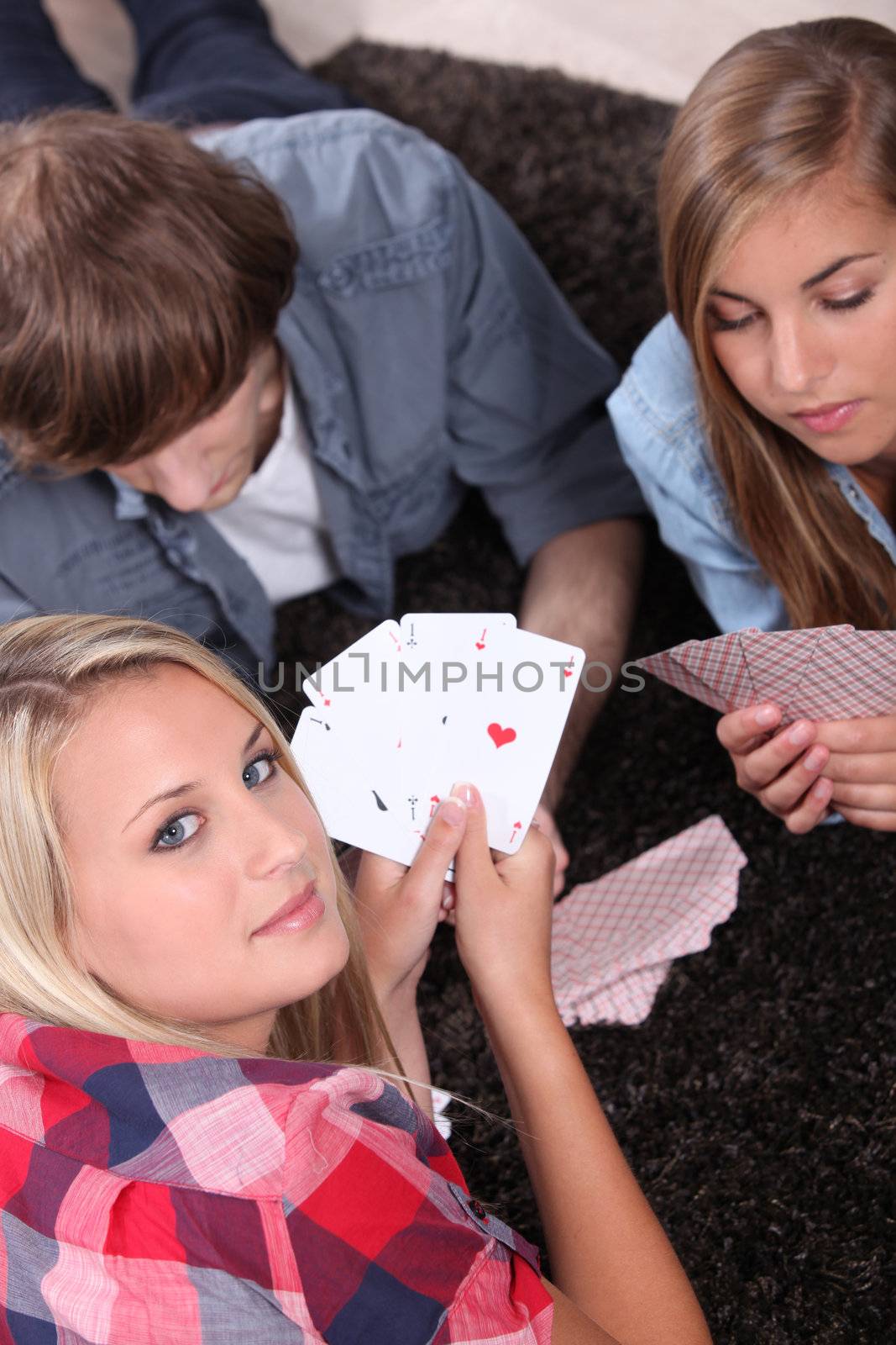 Young people playing cards with a girl showing the winning hand