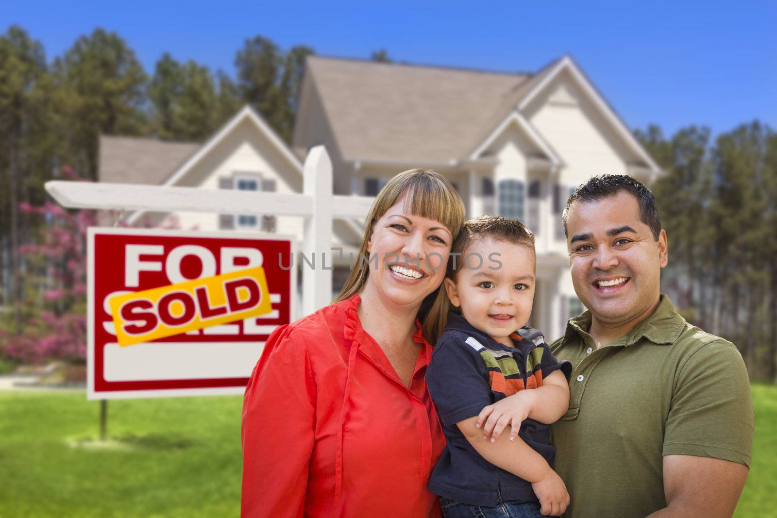 Mixed Race Young Family in Front of Sold Home For Sale Real Estate Sign and New House.