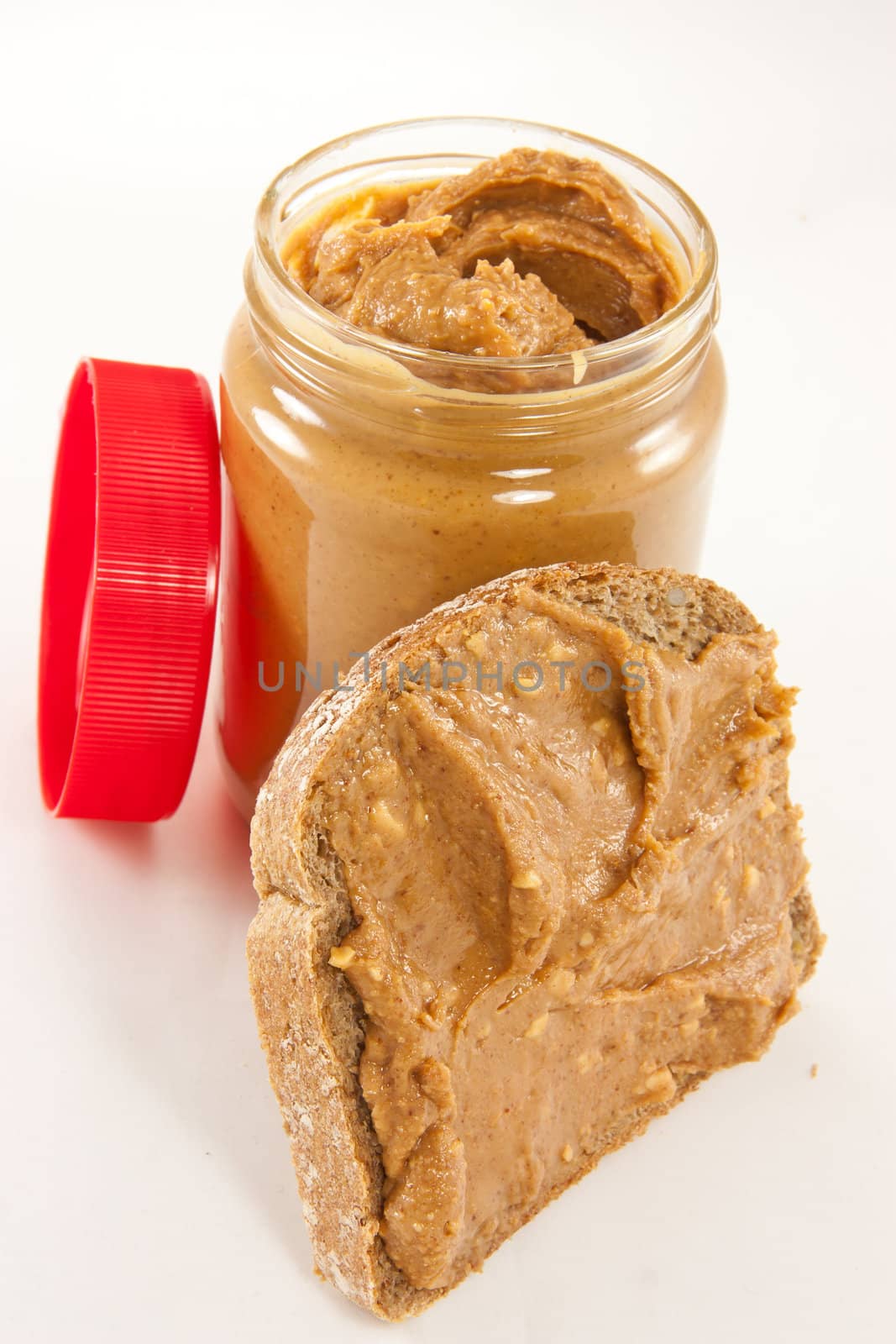 Picture of a slice of bread with some peanut butter on it, and a lid