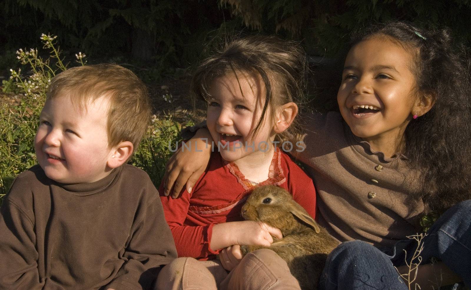 three laughing children and their little bunny