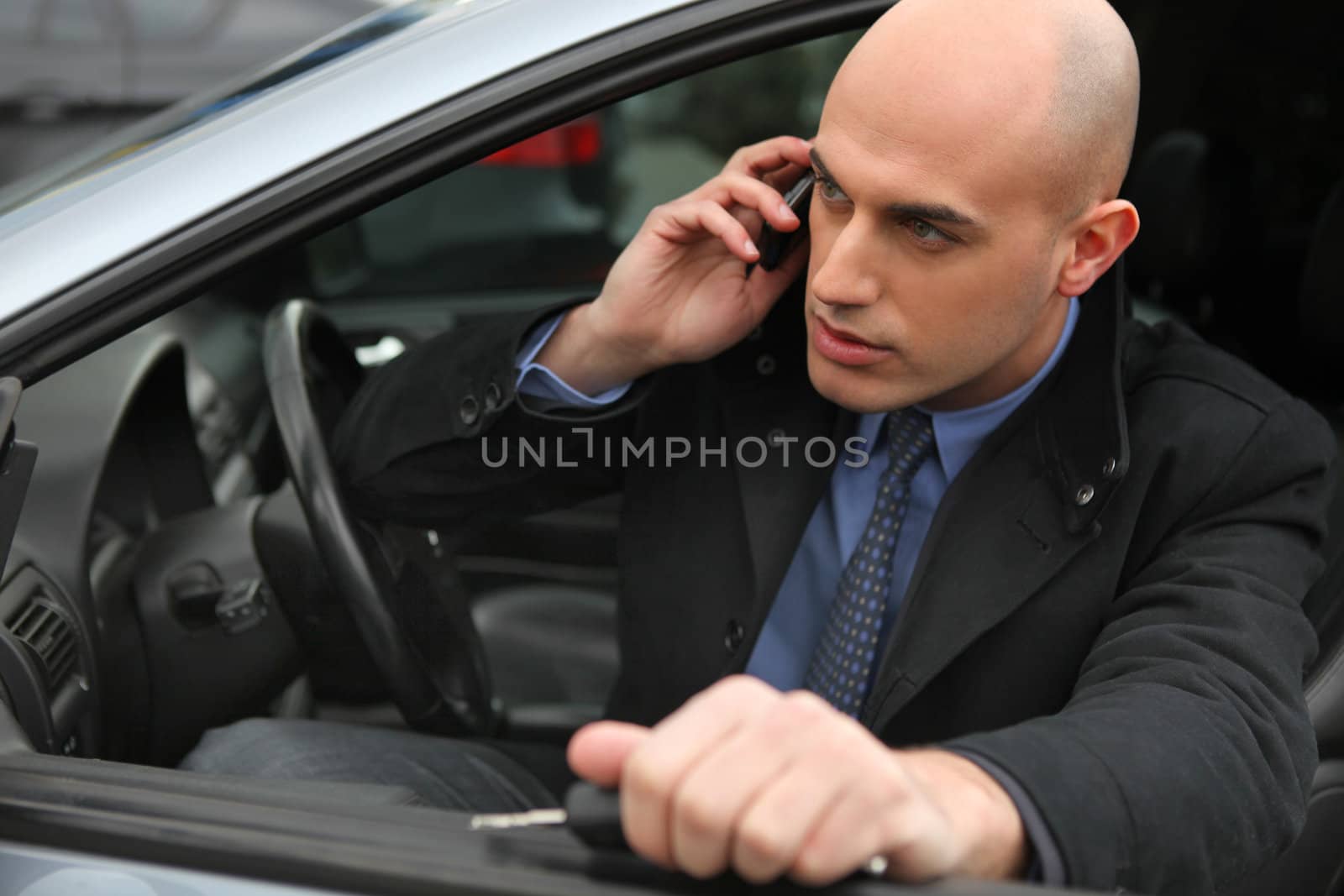 Businessman using a phone in his car by phovoir