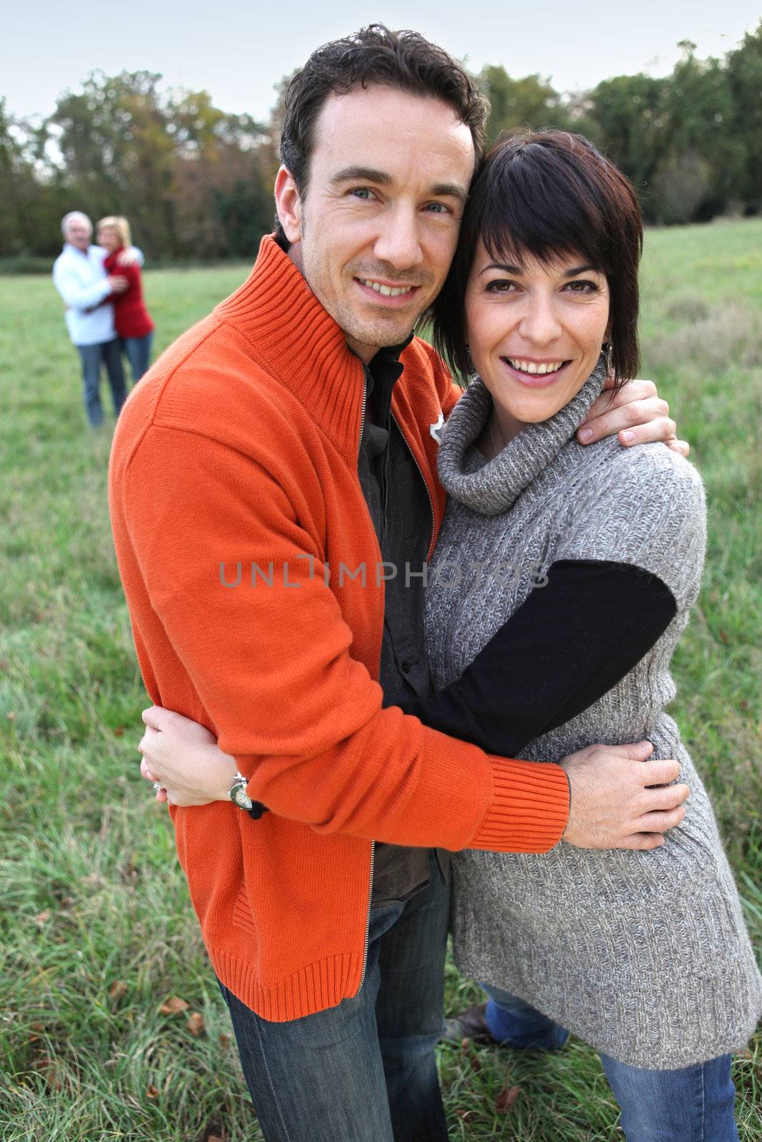 Two couples hugging in a field