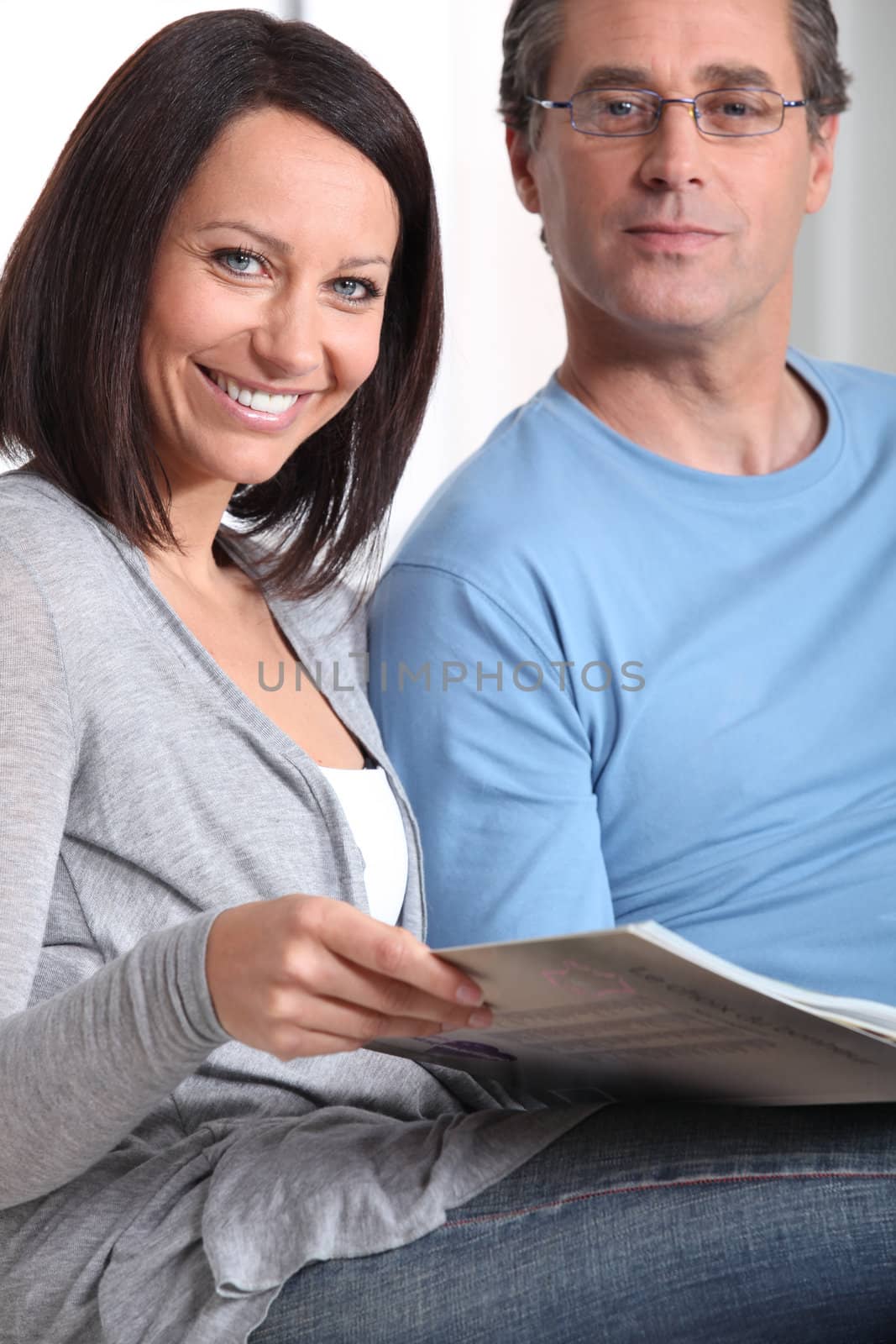 Couple reading through magazine together on sofa