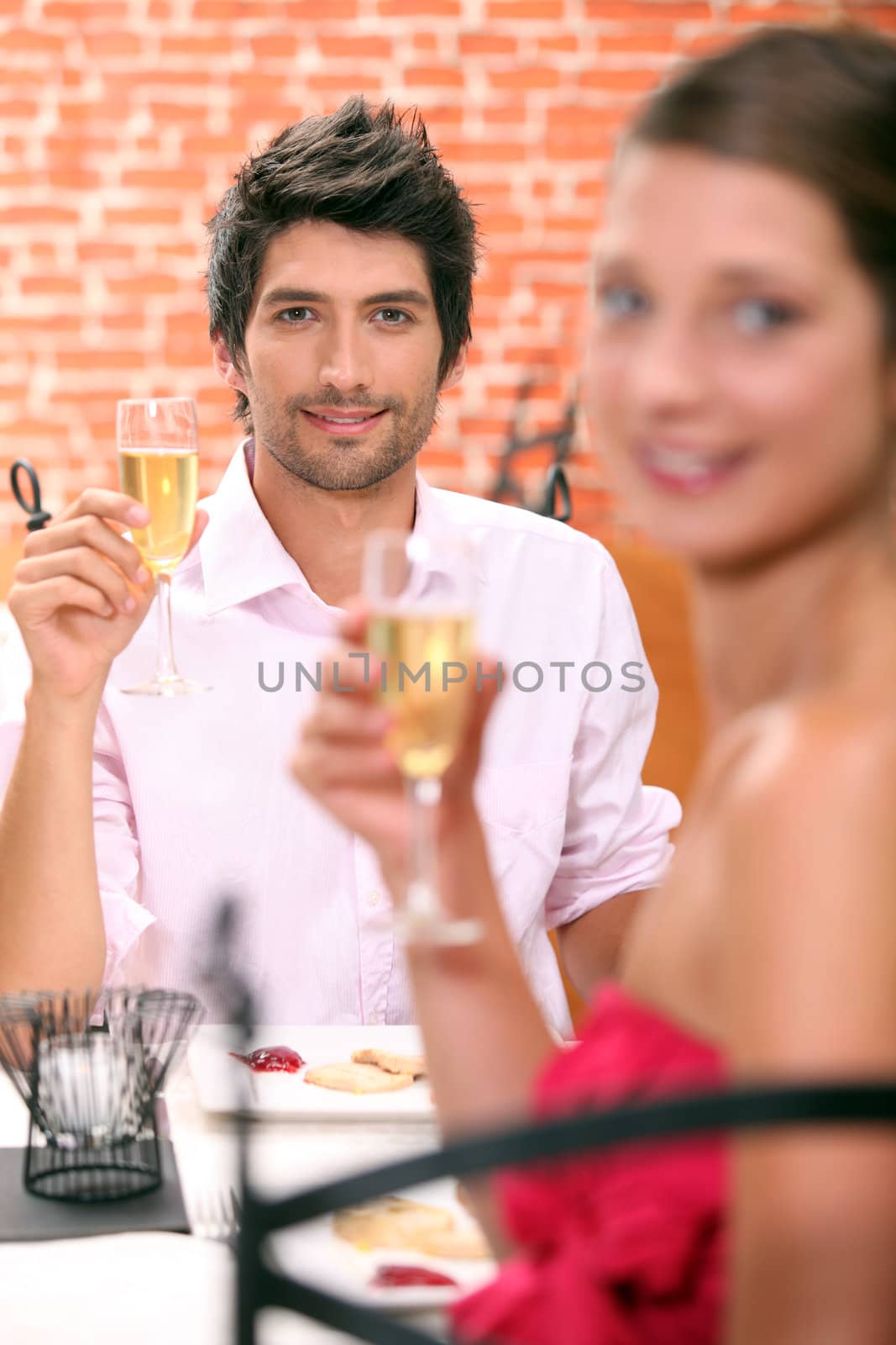 Couple in a restaurant with champagne by phovoir