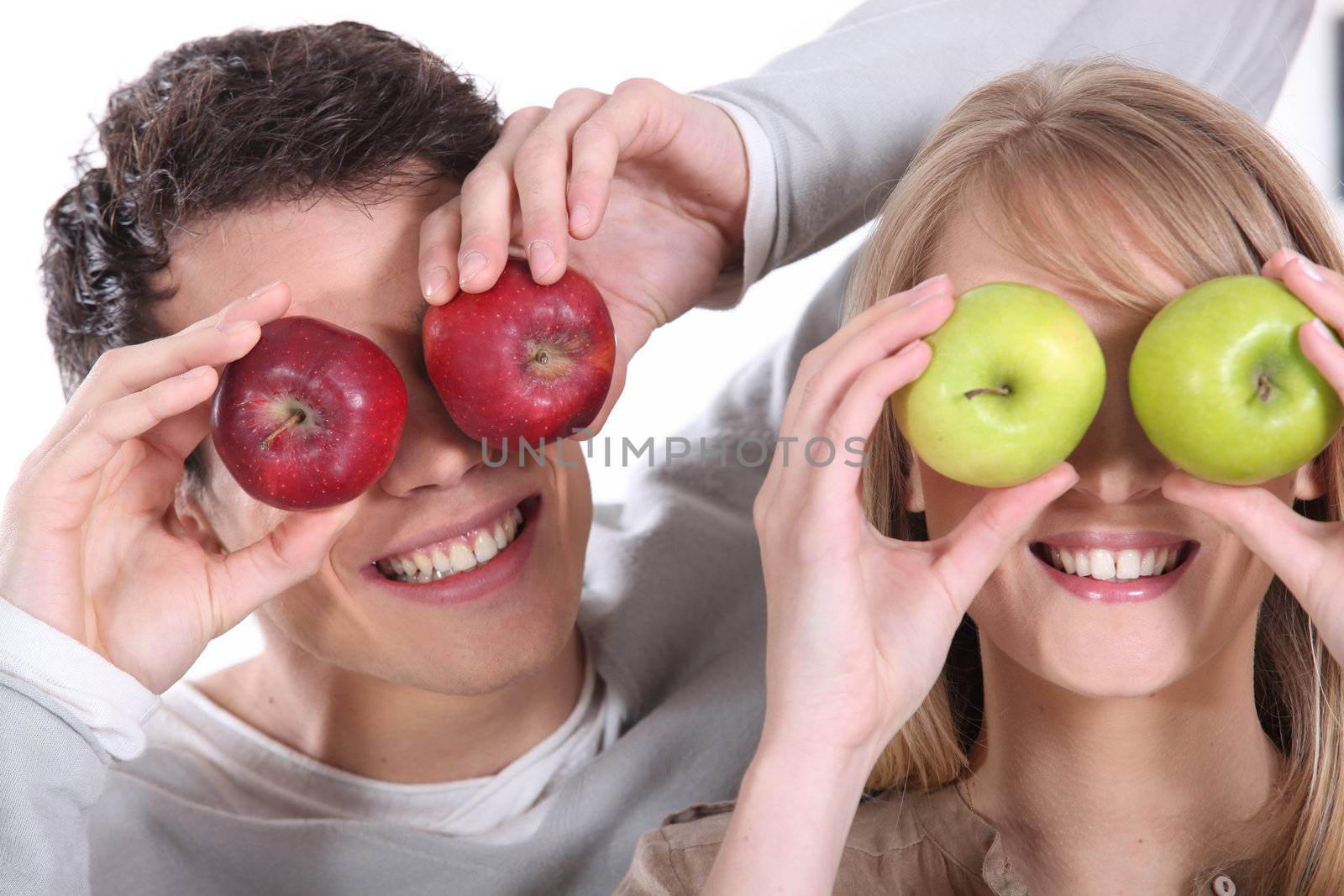 Man and woman covering her eyes with apples by phovoir