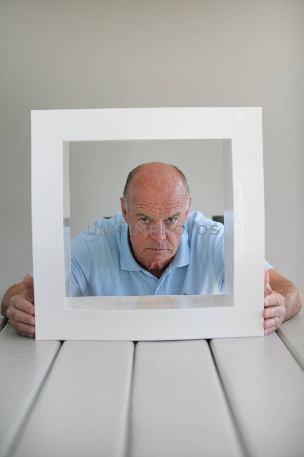 Senior man looking through a frame by phovoir