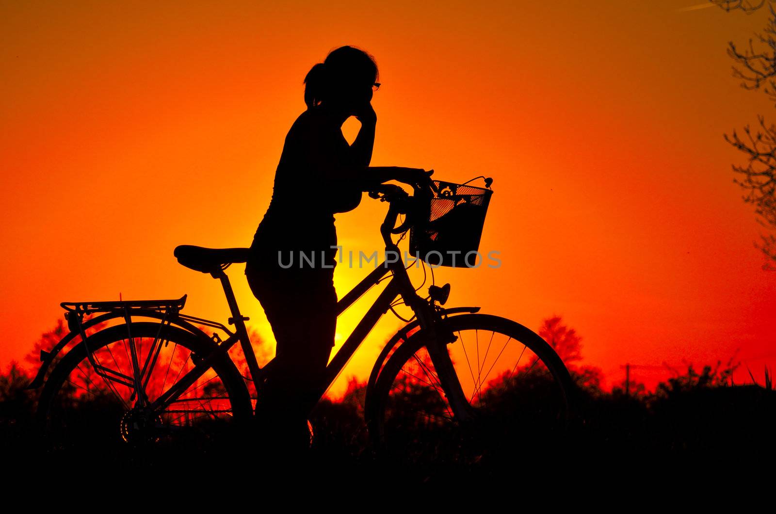 In the picture a young woman riding a bicycle, stopped to admire the splendor of the sunset.