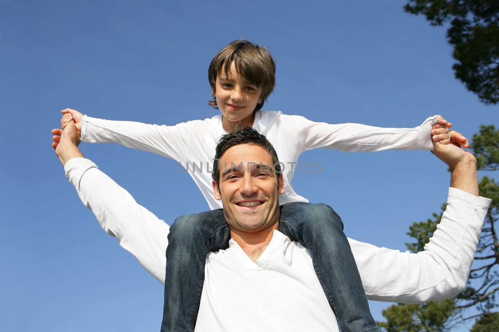 Child riding on his father's shoulders by phovoir