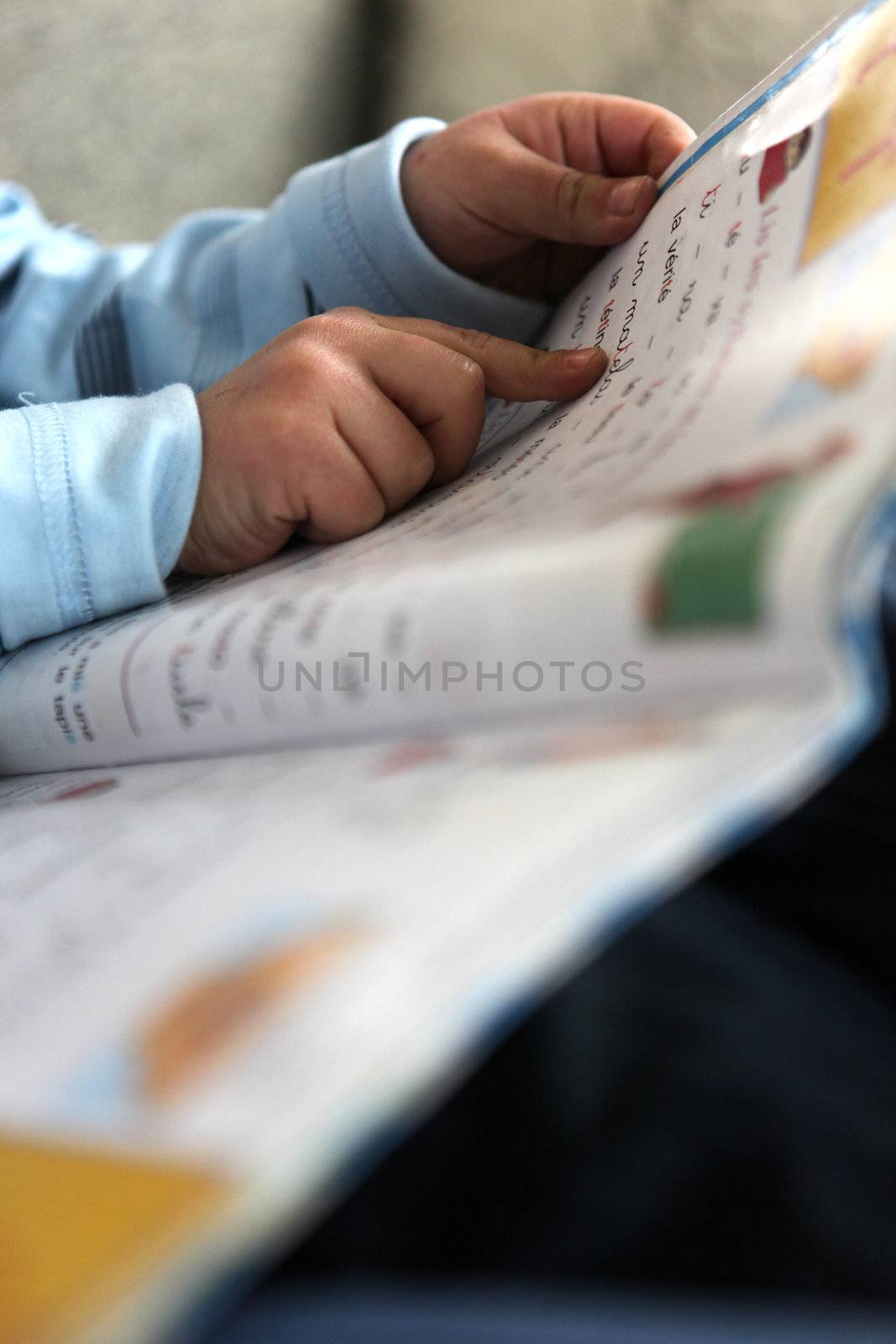 Close-up of toddler reading on the sofa by phovoir