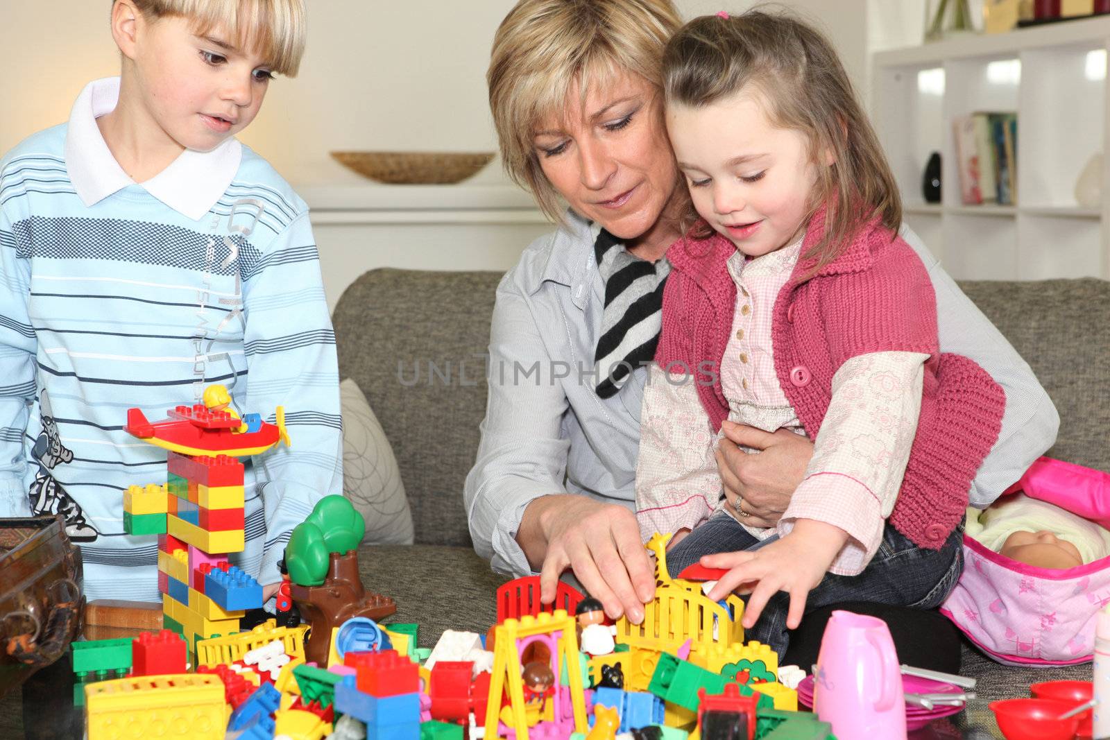 Mother and two children playing together by phovoir