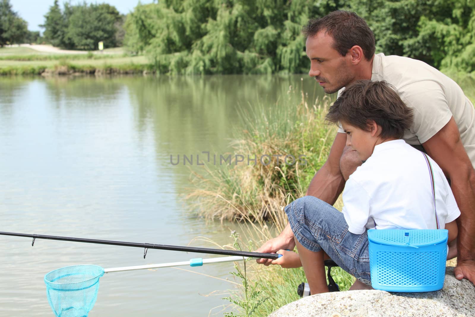 Father and son fishing together by phovoir
