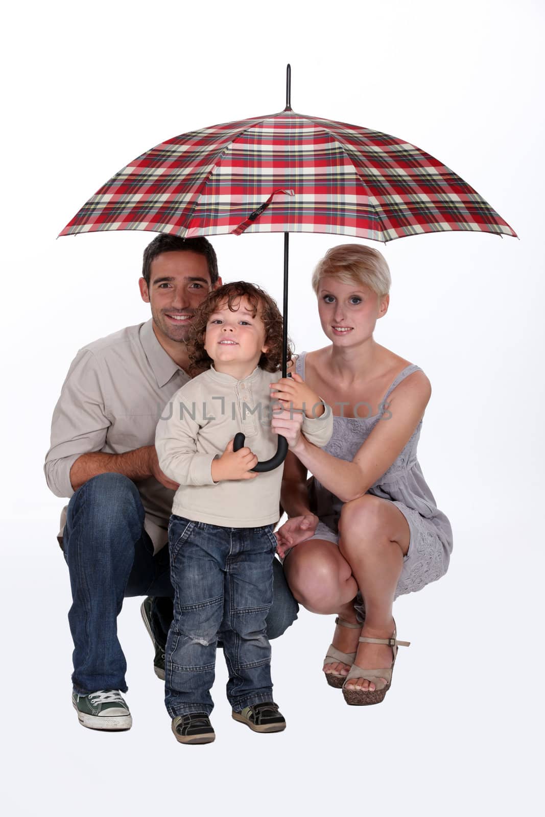 Young family sheltering under an umbrella