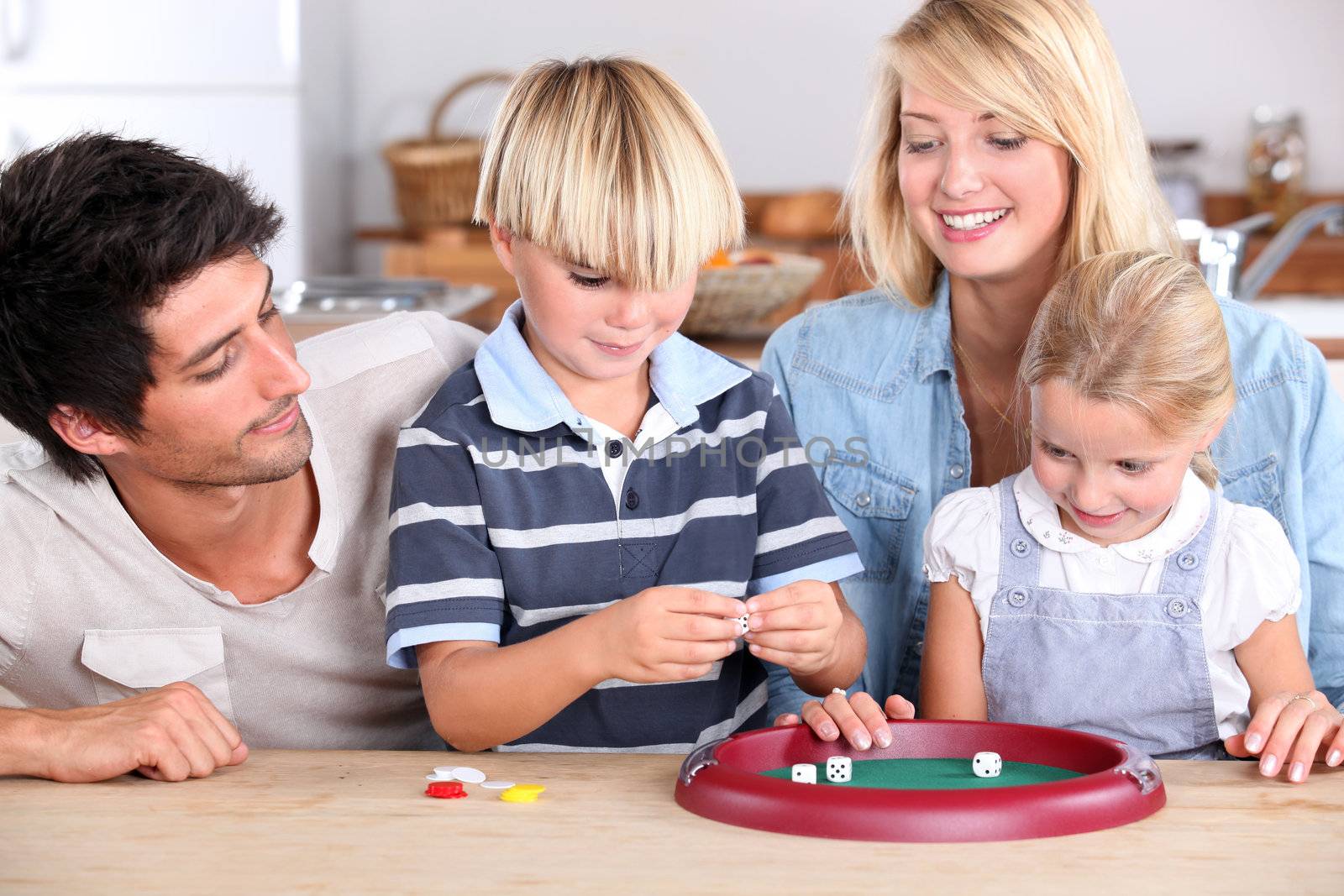 Family playing game at kitchen table by phovoir