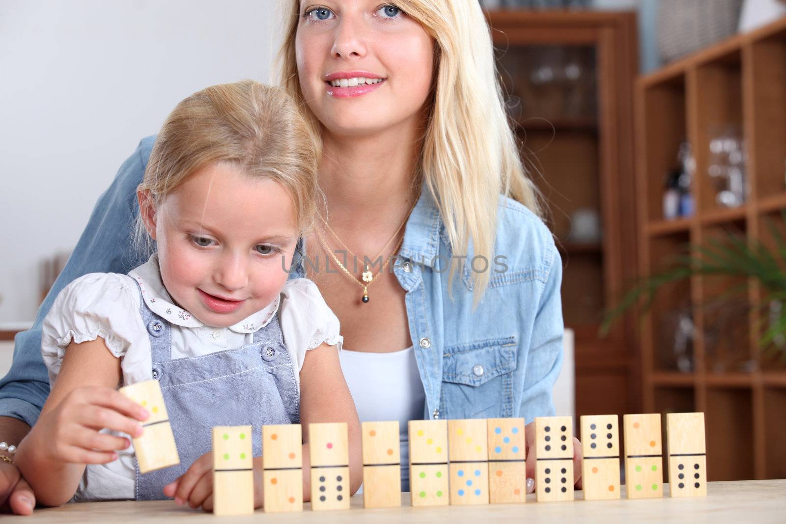 A mother and daughter playing with dominos.