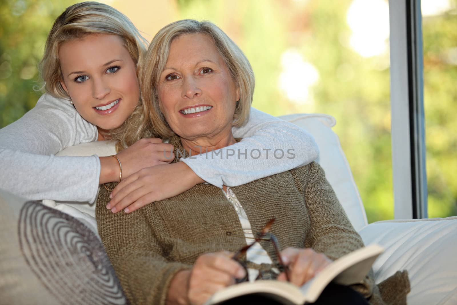 Girl with her grandmother reading a book by phovoir