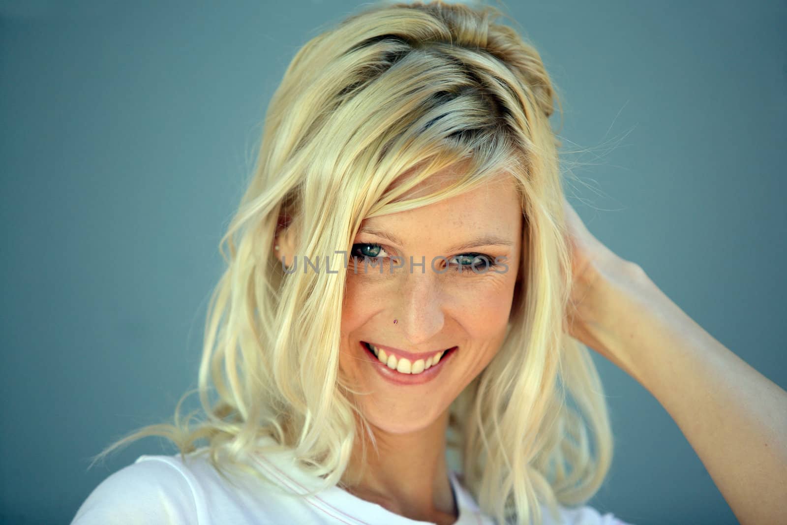 Coy blond woman touching hair by phovoir