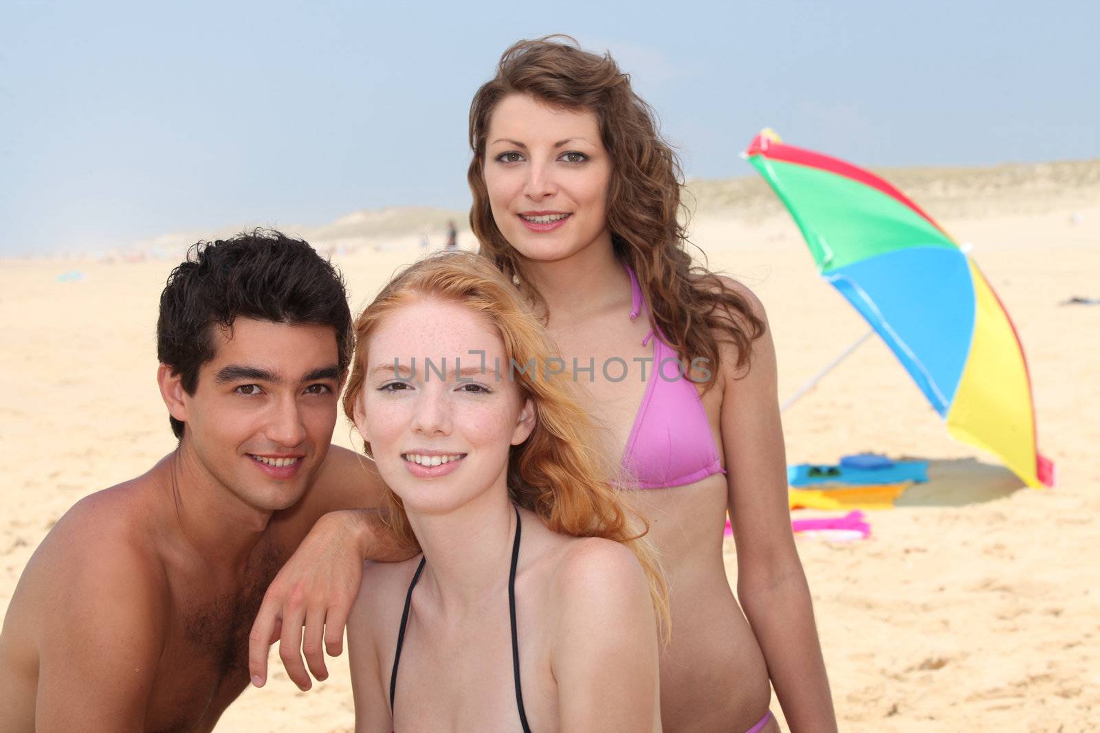 three friends having fun on the beach by phovoir