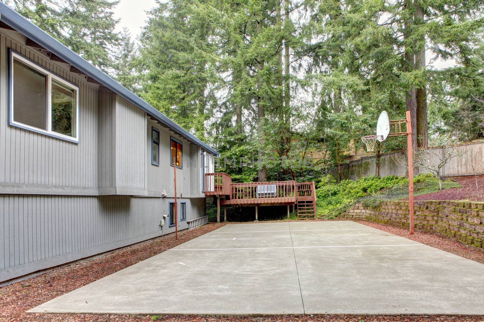 Grey house with backyard with basket ball area.