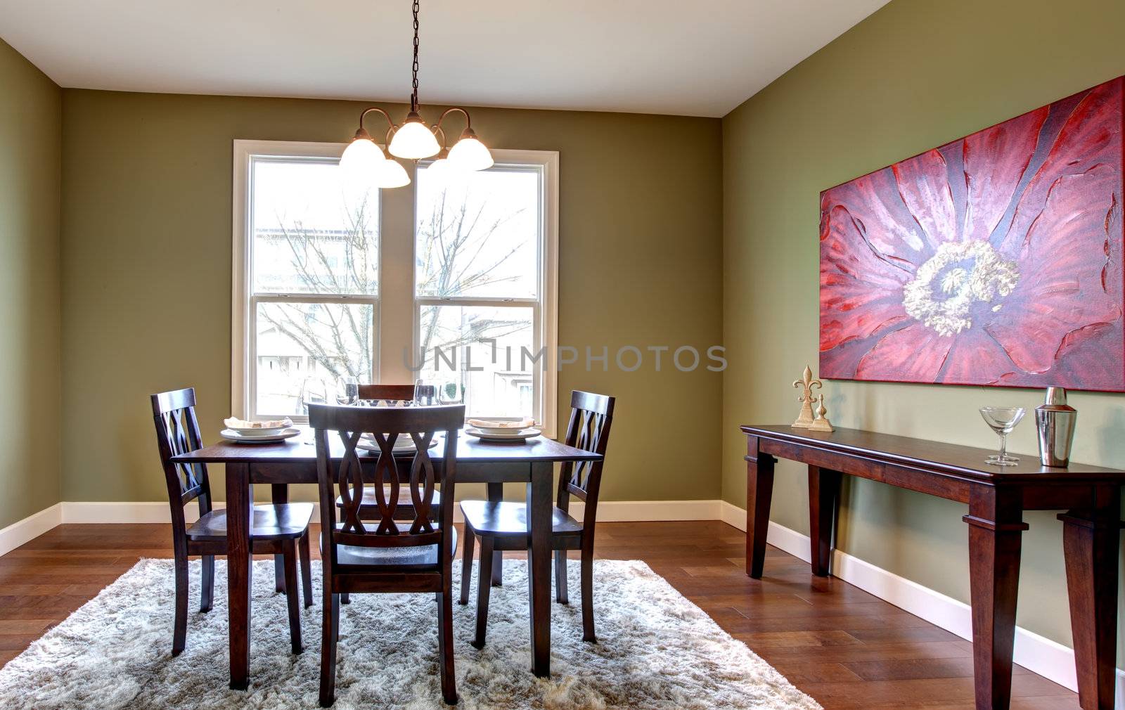 Beautiful and nice dining room with green walls and red paainting.