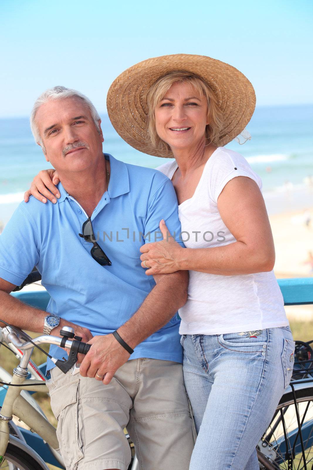 Middle-aged couple enjoying bike ride by the sea