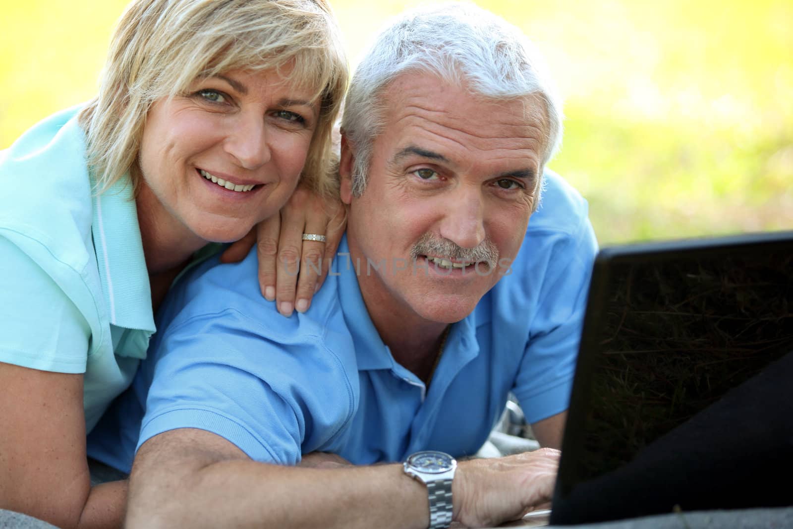 portrait of smiling mature couple with laptop outdoors