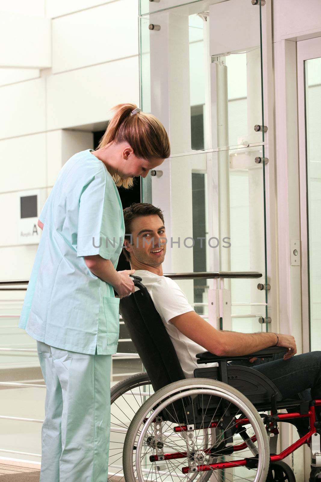 Nurse and patient in wheelchair in front of a lift by phovoir