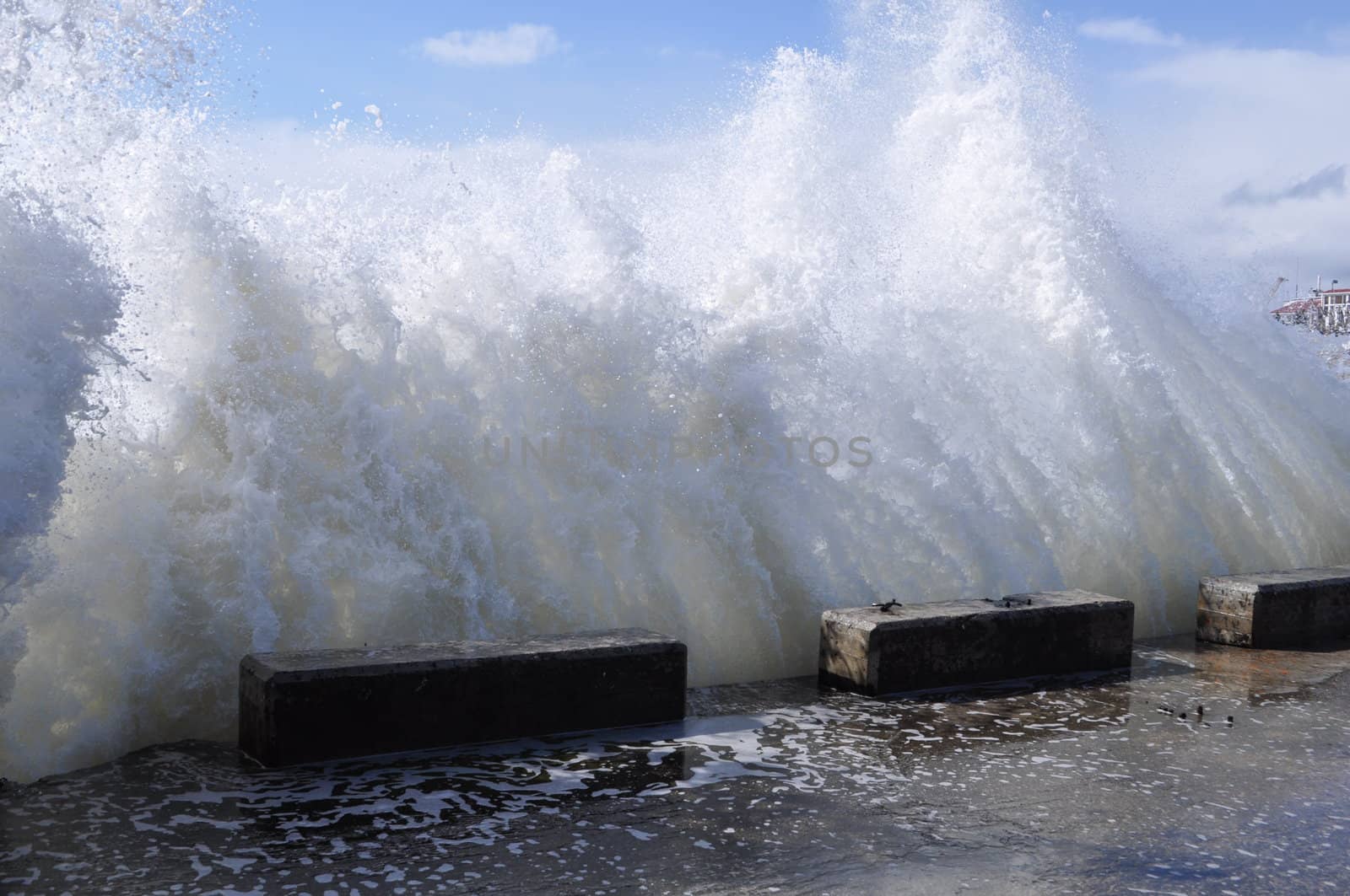 Sea waves breaking on concrete port with spray