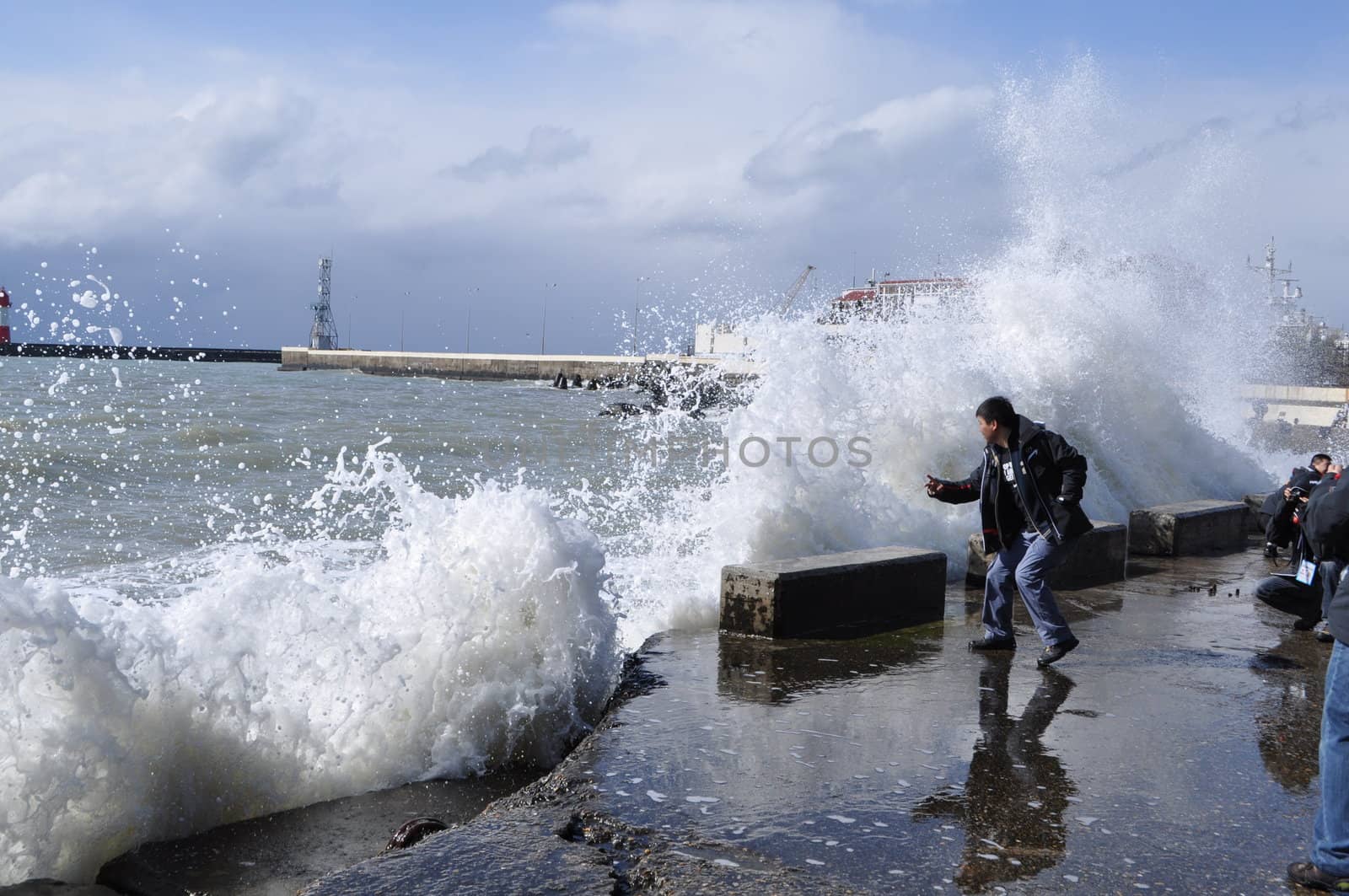 Sea waves breaking on concrete port with spray