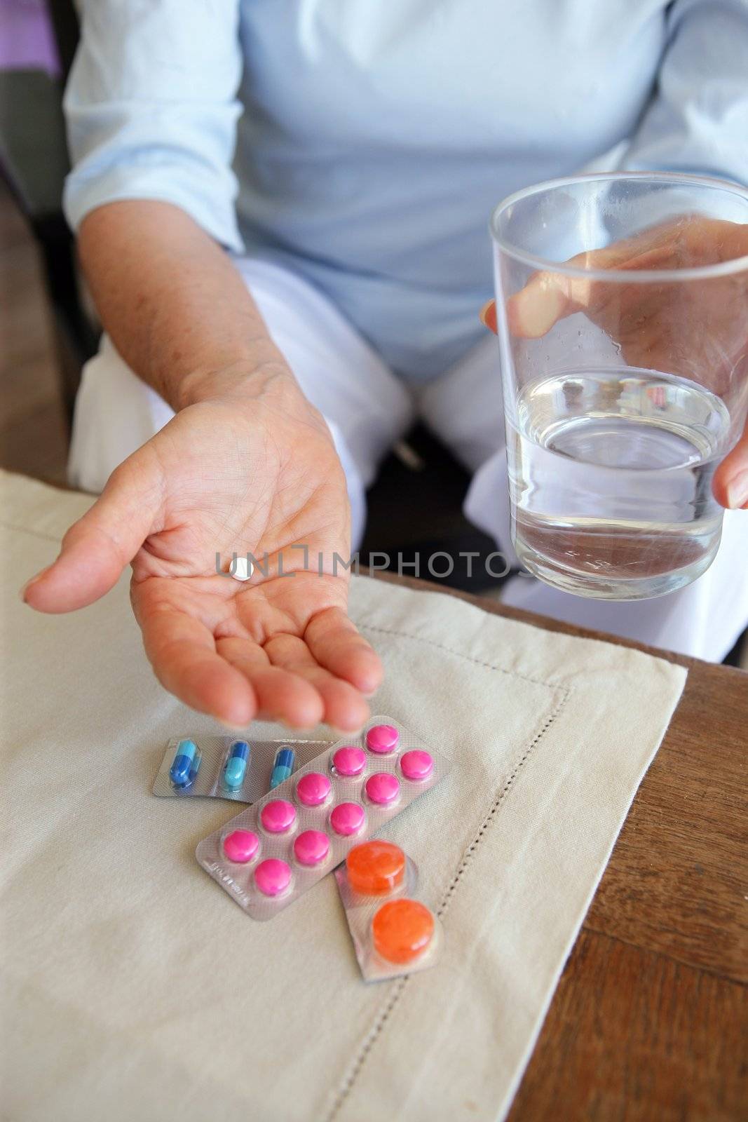 Woman taking her medication with a glass of water by phovoir