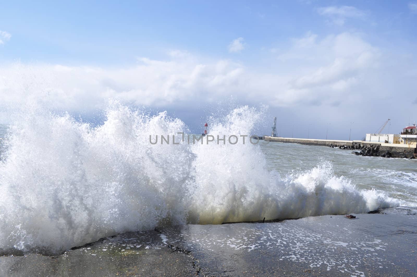 Sea waves breaking on concrete port with spray