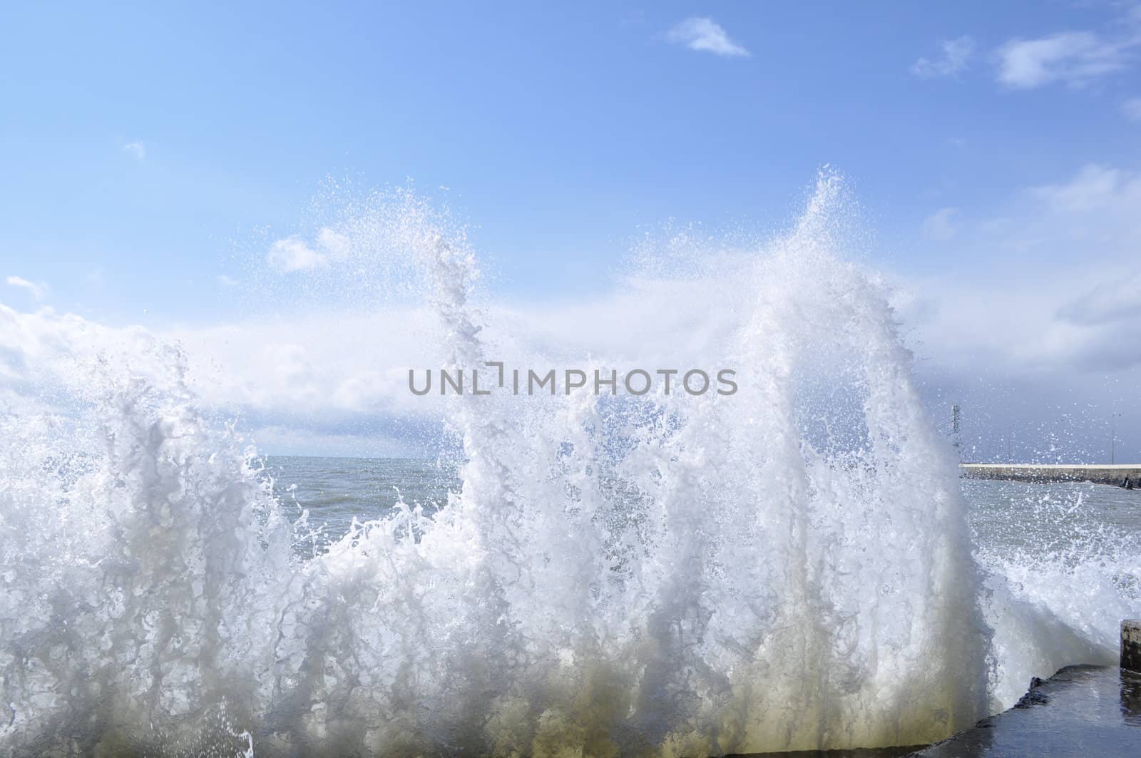 Sea waves breaking on concrete port with spray