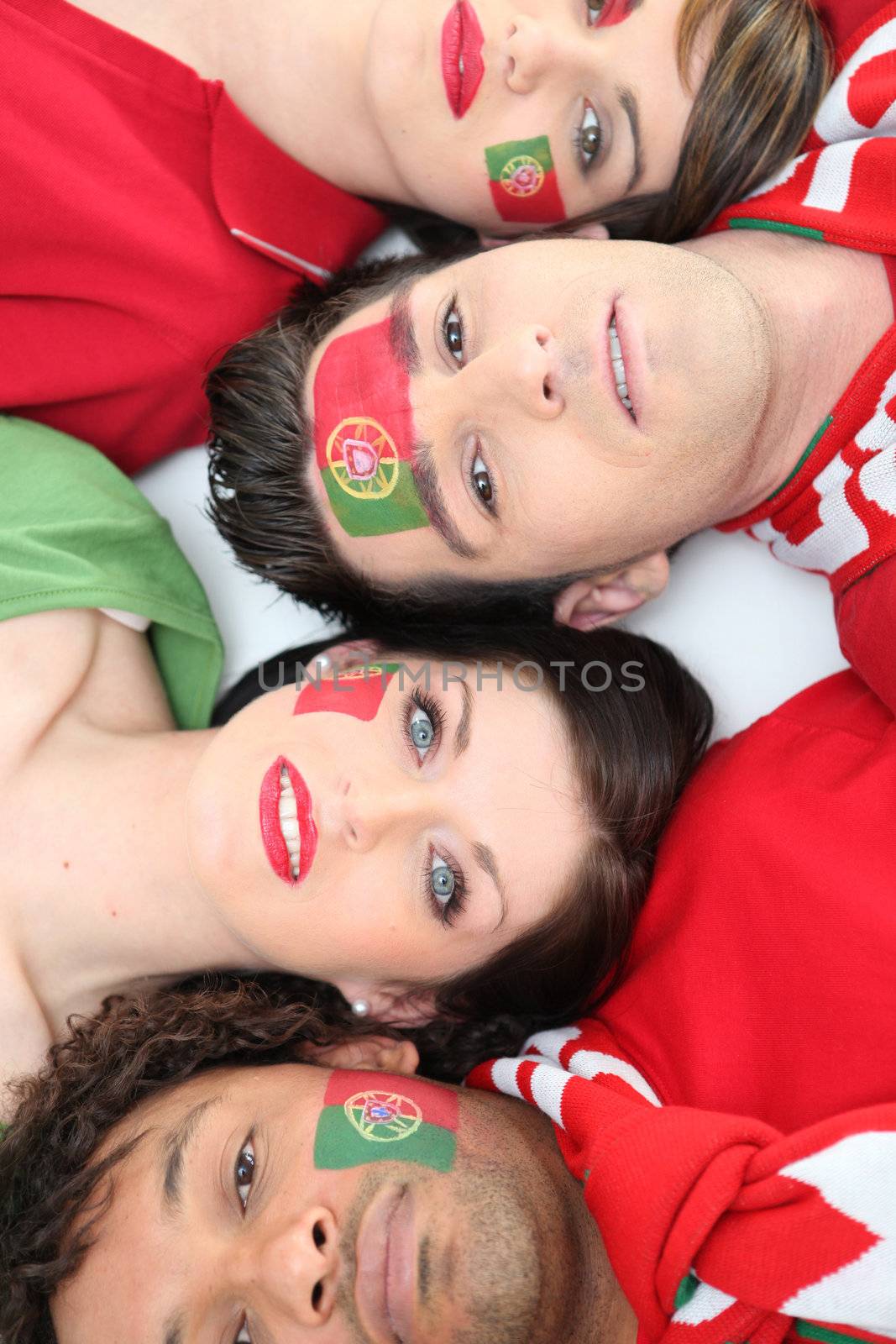 Four Portuguese soccer fans laying down together
