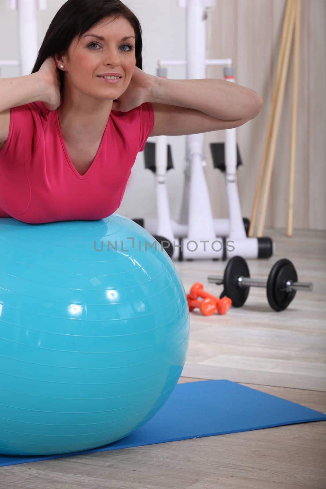 Woman working out with the help of an exercise ball by phovoir