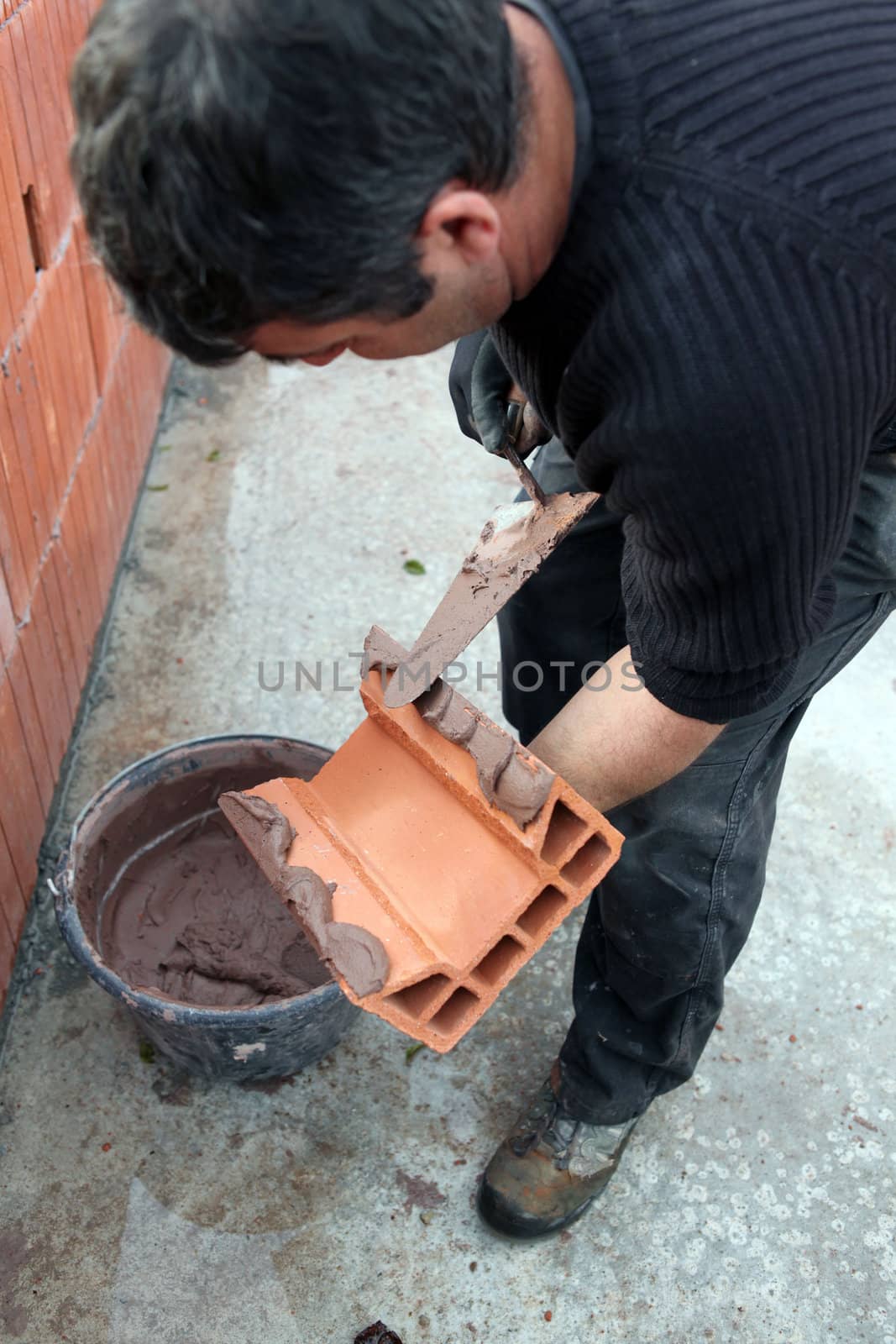 Mason applying cement on a cinderblock by phovoir