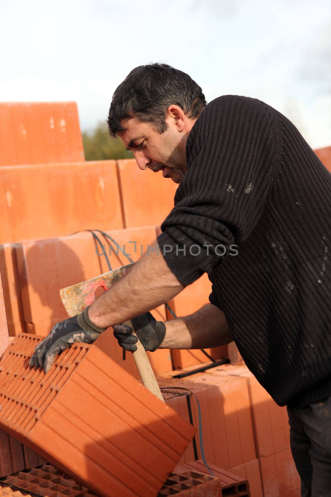 Mason making adjustments to brick by phovoir