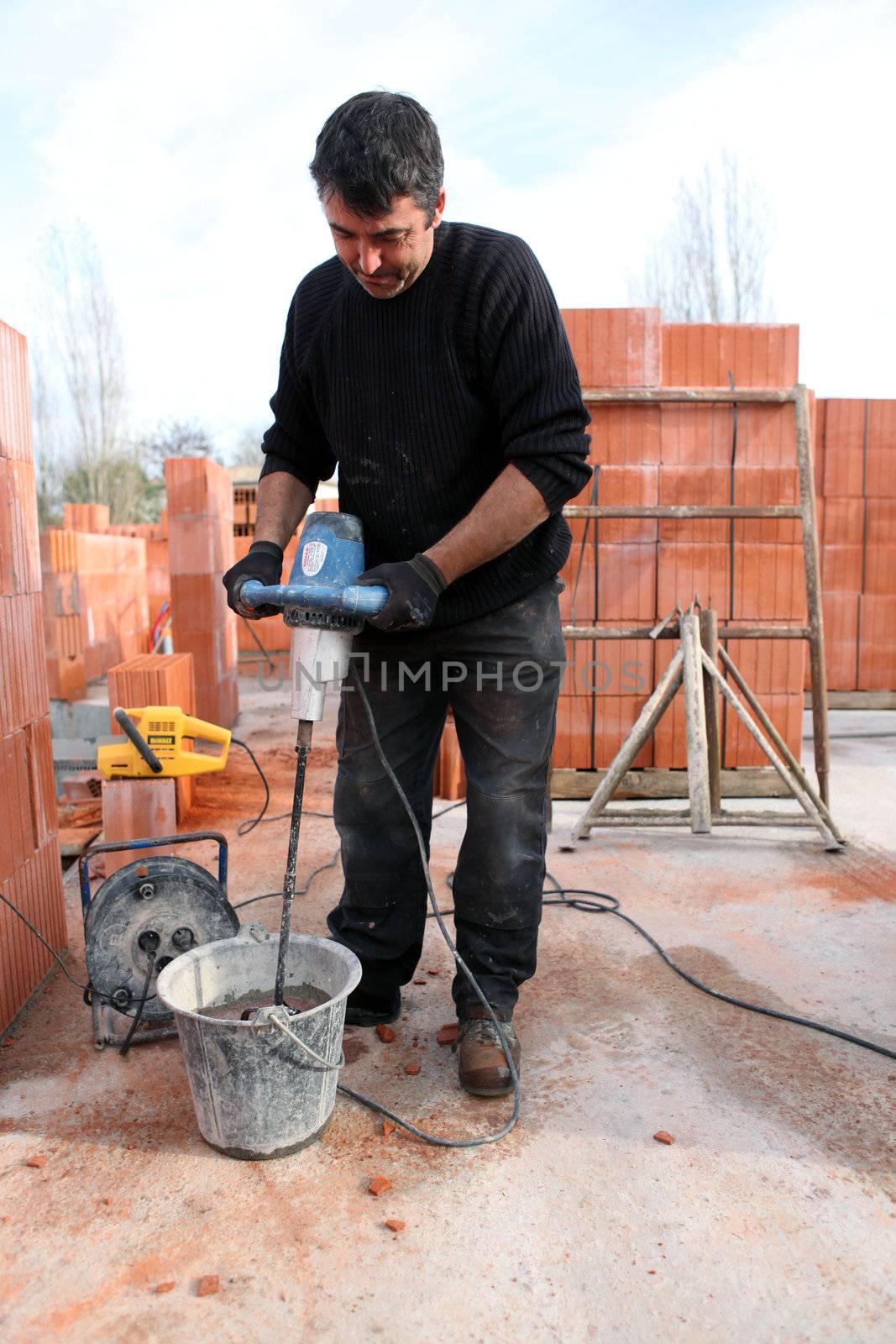 Workman using a cement paddle whisk