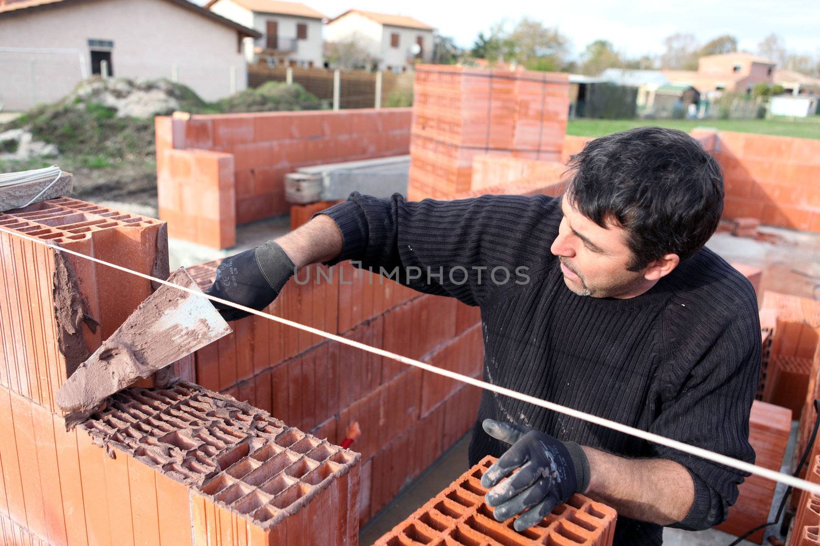 Bricklayer building a house by phovoir