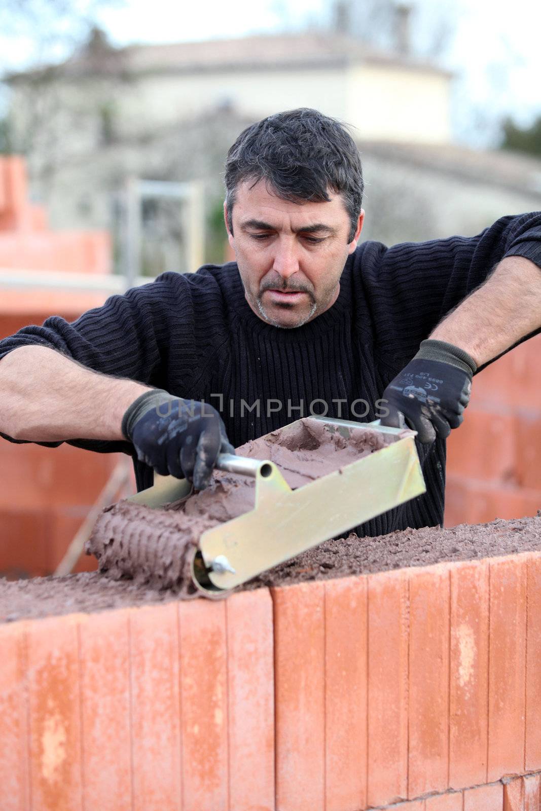 Bricklayer building a house by phovoir