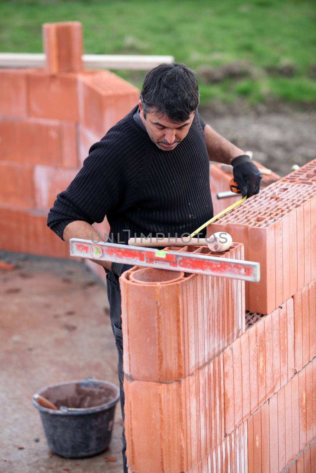bricklayer erecting red brick wall