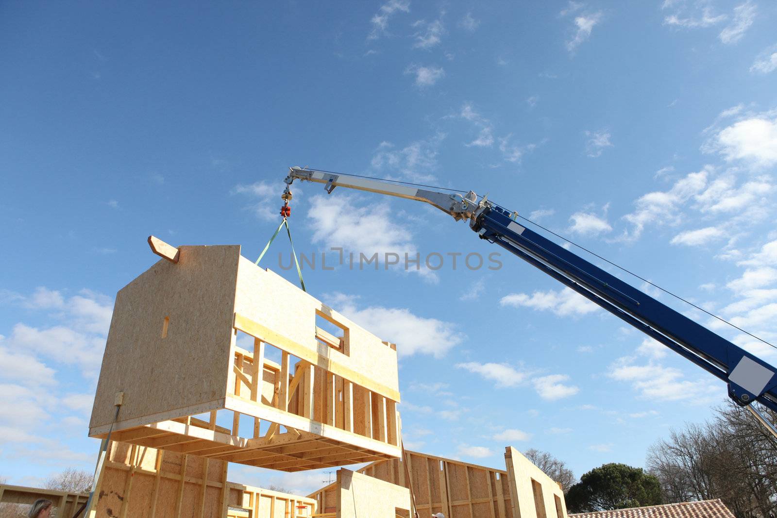 Crane lifting the framework of a house by phovoir