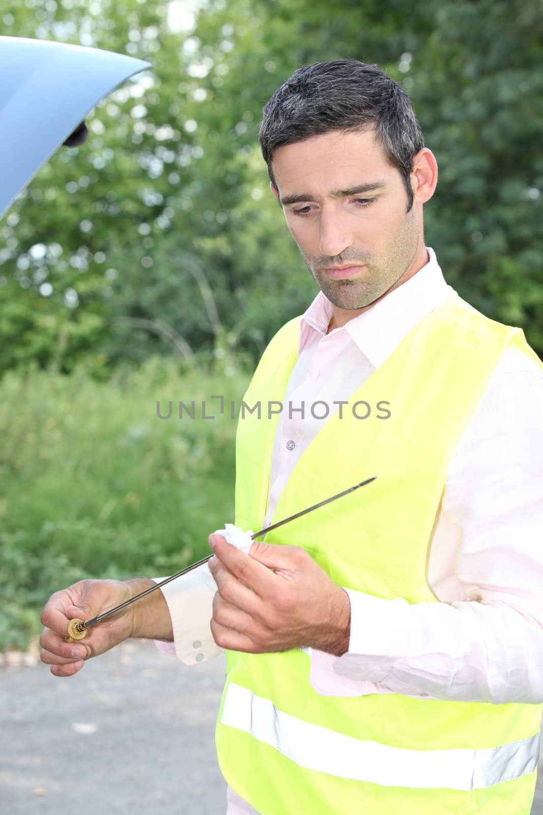 Man checking his oil dipstick by phovoir