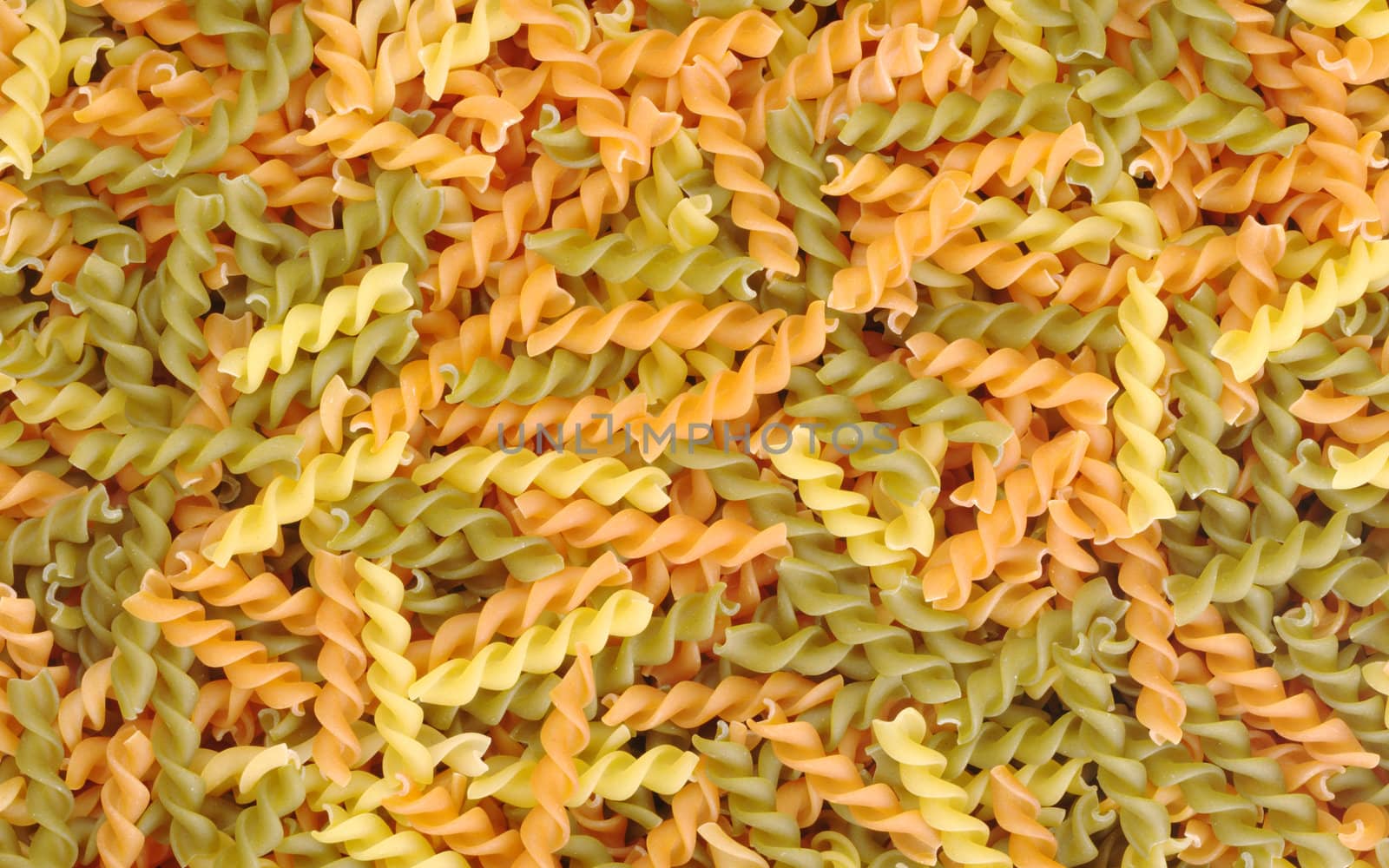 Uncooked pasta (Fusilli) in different colour as background
