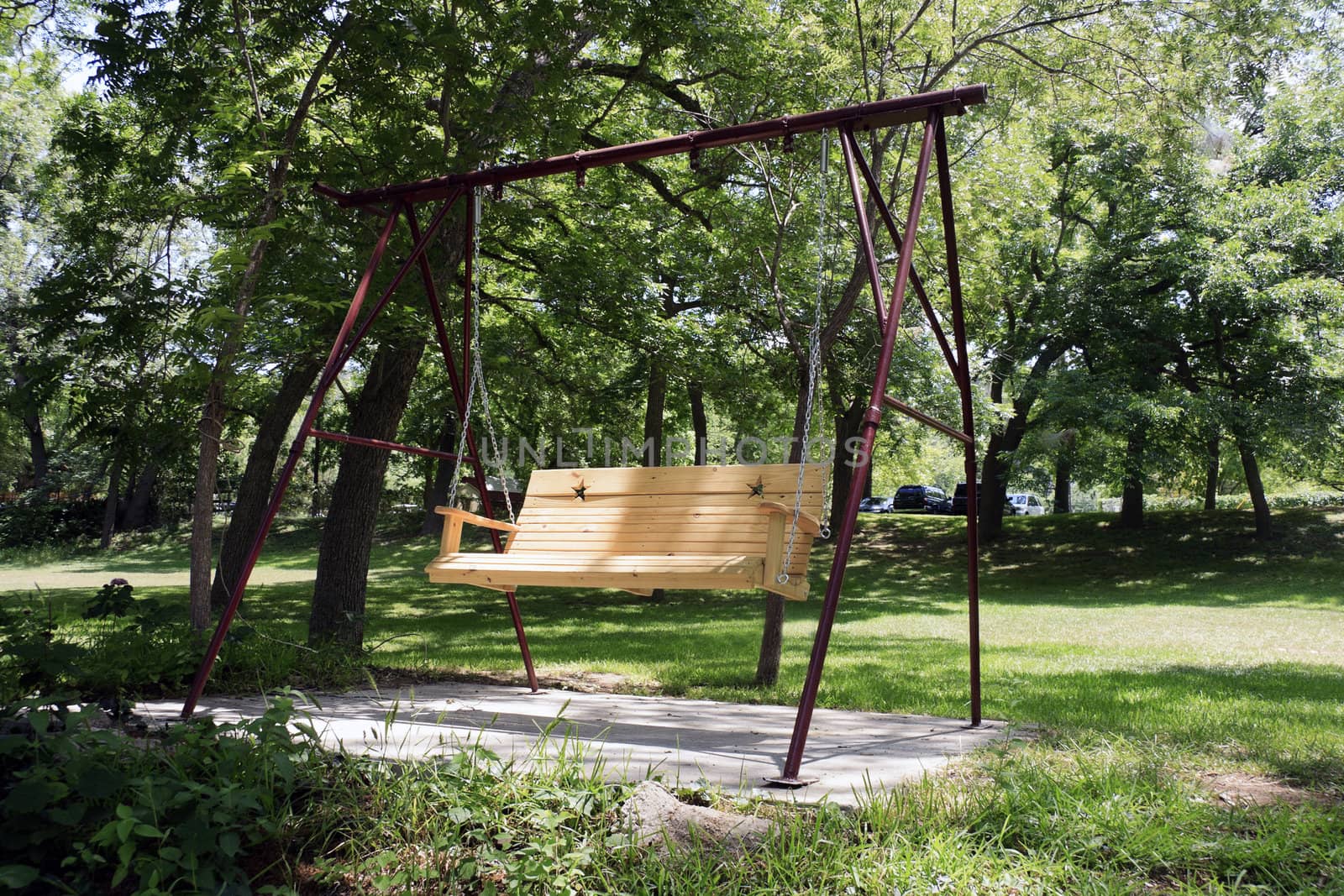An empty wooden swing out in a garden 