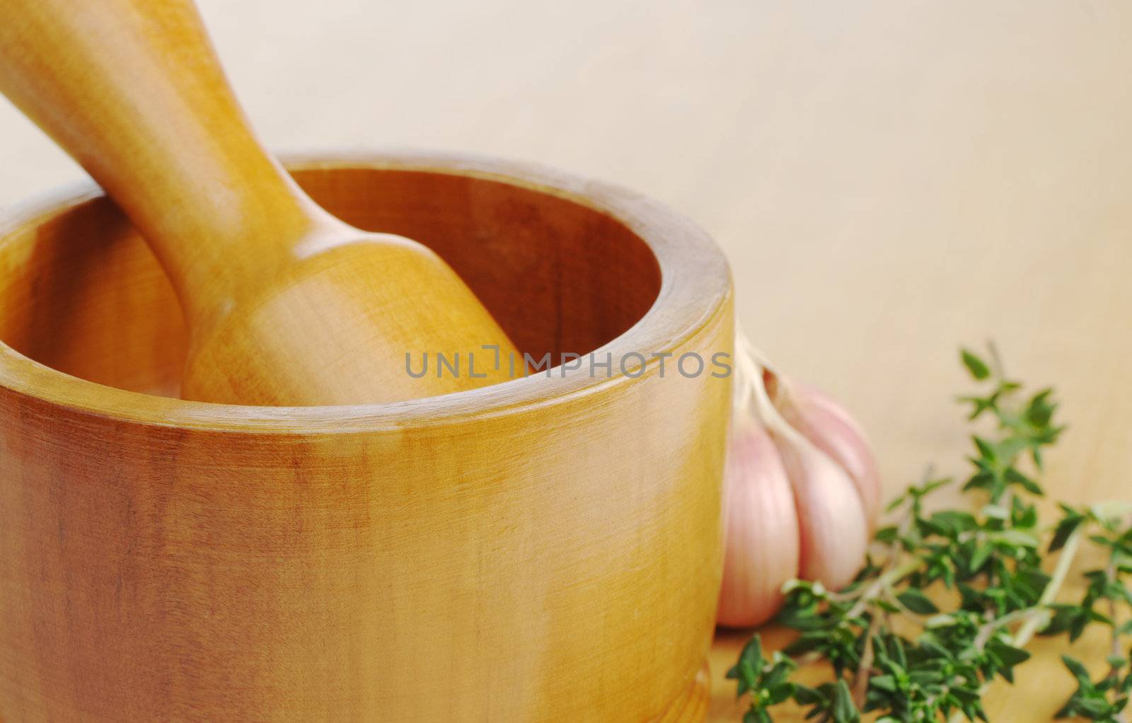 Wooden mortar on wooden board with garlic and thyme (Selective Focus)
