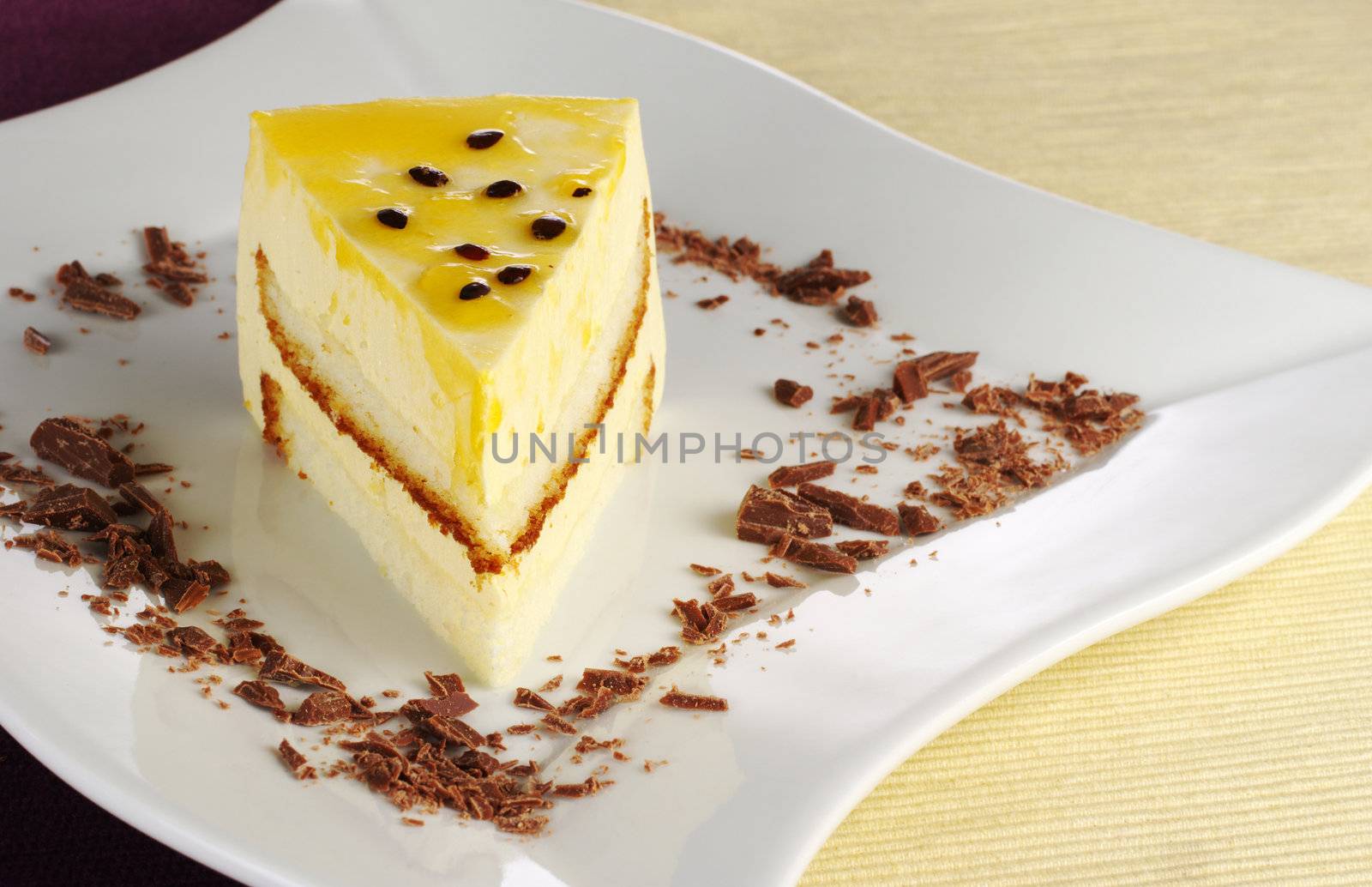 A piece of passionfruit cake with chocolate shavings on white plate (Selective Focus)