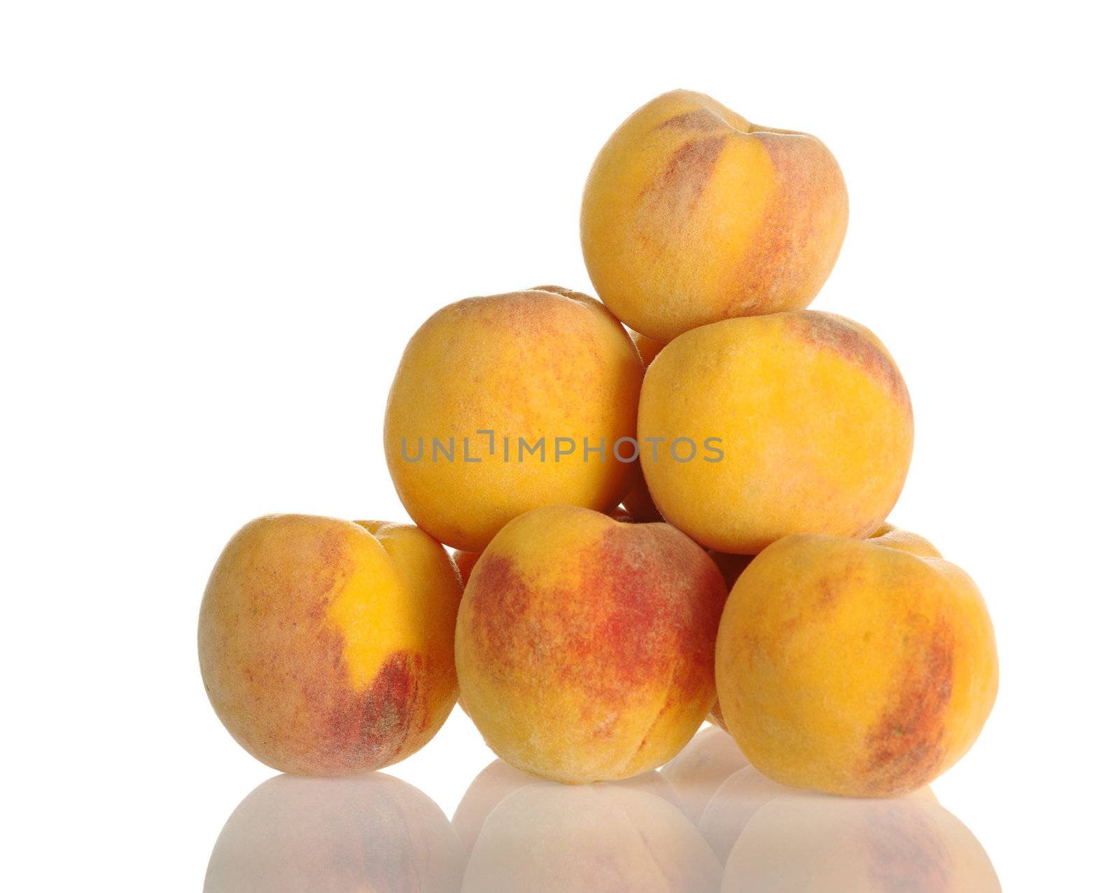 A pile of yellow-red colored peaches with reflection photographed on white (Selective Focus, Focus on the upper two rows)