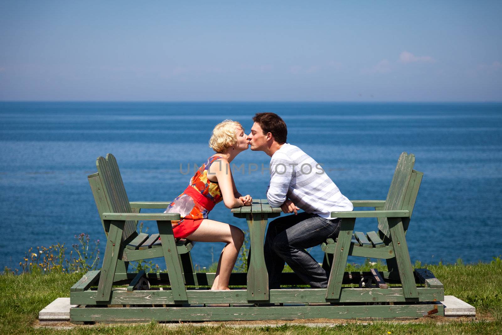 Romantic couple kissing on the bench in vacation