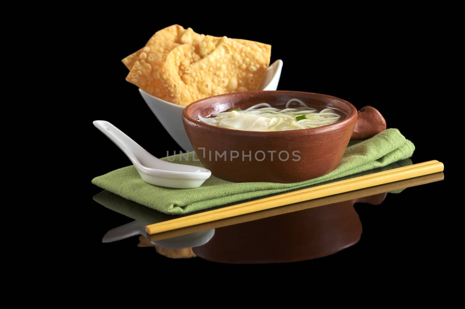 Chinese noodle soup with deep-fried wonton appetizer, ceramic spoon and chopsticks (Selective Focus, Focus on the front of the soup bowl)