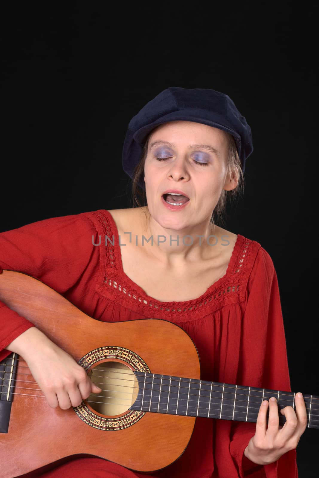 Young Caucasian woman singing and playing the guitar (Selective Focus, Focus on the face, hands and the guitar)